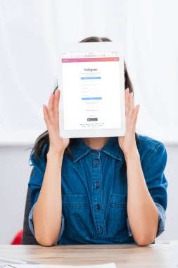 Genç kadın tarafından dijital tablet instagram Web sitesinde ekran ile yüz kapsayan