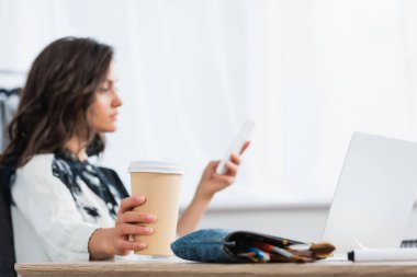 Kağıt bardak kahve masada smartphone kullanarak kadın moda tasarımcısının elinde seçici odak 