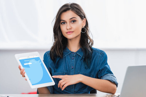 attractive young woman pointing on digital tablet screen with twitter website 