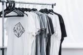 selective focus of t-shirts with print on hangers in clothing design studio 