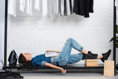 kadın moda tasarımcısı beyaz t-shirt ve giyim tasarım stüdyosu paketinde kağıt yığını ile döşeme yan görünüm