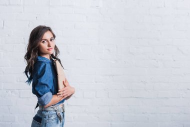 Kağıt paket tuğla duvar önünde tutan çekici genç kadın 