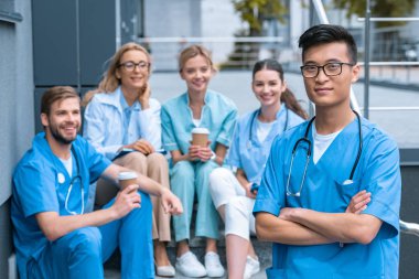 Asya adam beyaz öğretmen ve öğrencilerin Tıp Üniversitesi'nde önünde ayakta 