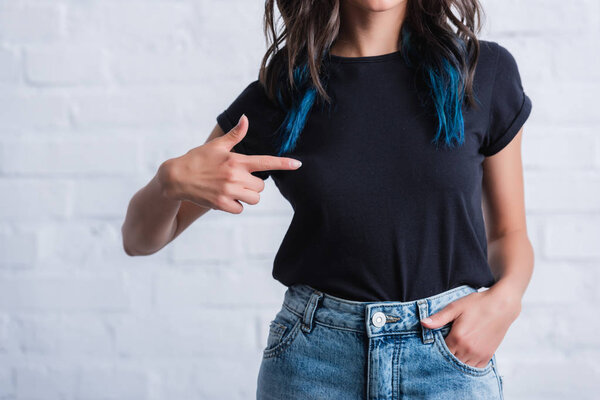 cropped image of young woman pointing by finger on empty black t-shirt 