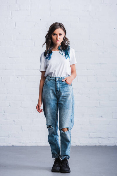 front view of young woman in empty white t-shirt in front of brick wall 