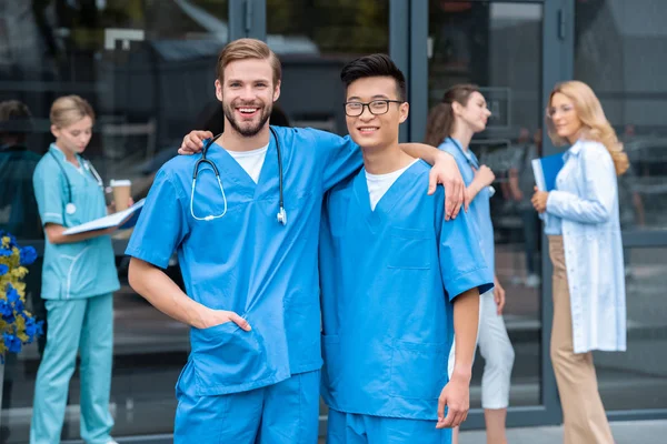 Estudantes Multiculturais Abraçando Olhando Para Câmera Perto Universidade Médica — Fotografia de Stock