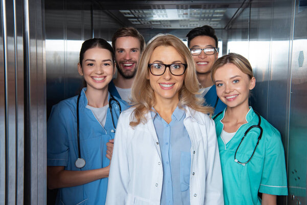 happy teacher and multicultural students standing in elevator at medical university