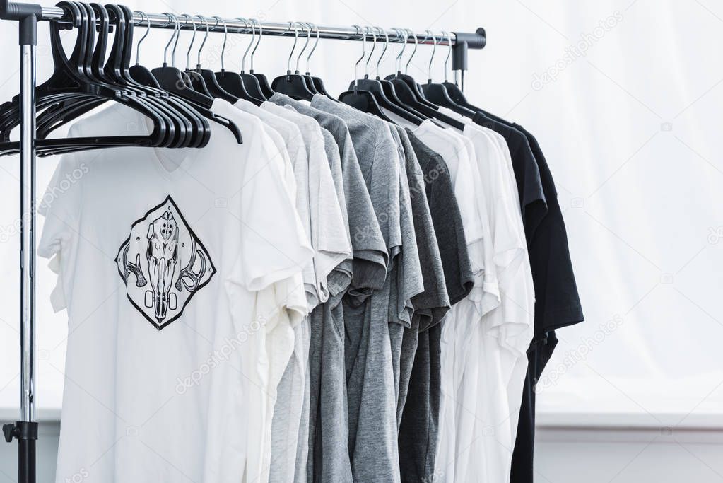 Selective focus of t-shirts with print on hangers in clothing design studio