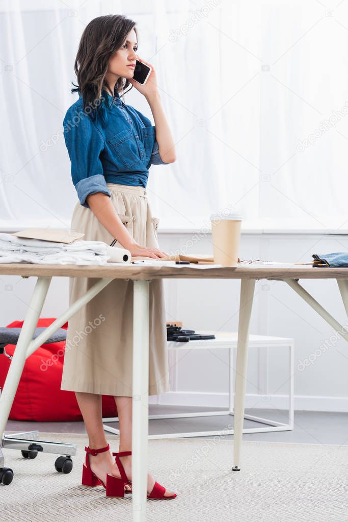 female fashion female fashion designer talking on smartphone in clothing design studio
