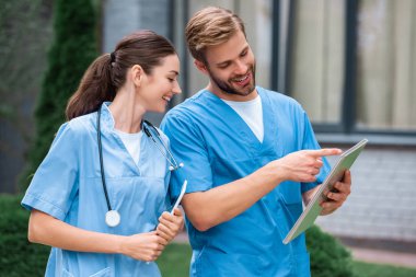 handsome medical student pointing on something in notebook to friend on street clipart