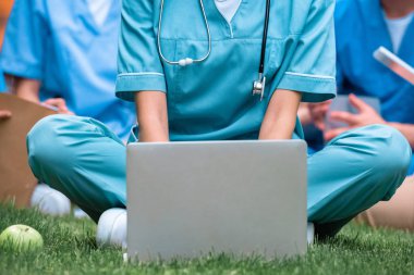 cropped image of medical student studying with laptop on green grass clipart