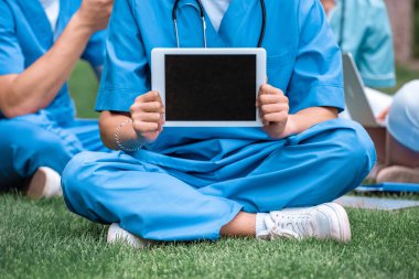 cropped image of medical student holding tablet with blank screen clipart