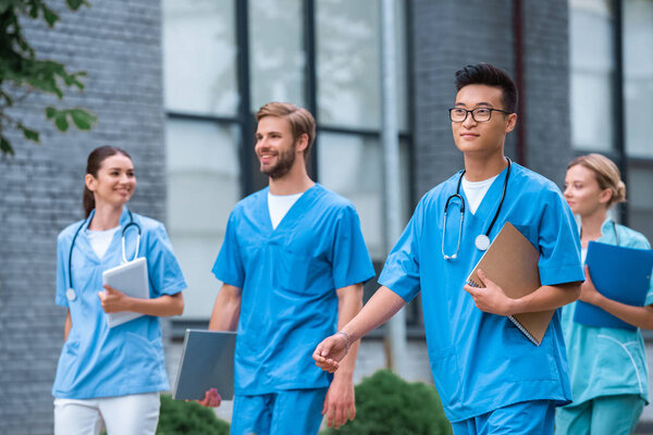 cheerful multicultural medical students walking near medical university