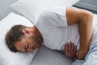 adam yatakta yatan ve mide ağrısı acı yüksek açılı görünüş