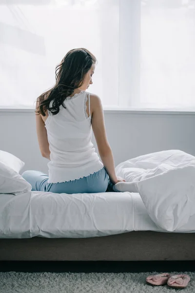 Widok Młoda Brunetka Kobieta Piżamie Siedząc Łóżku Patrząc Dół Tyłu — Zdjęcie stockowe