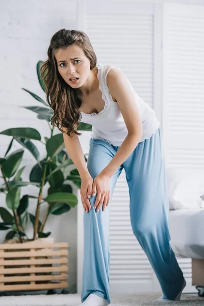 Jovem Mulher Pijama Sofrendo Dor Joelho Olhando Para Câmera Quarto — Fotos gratuitas