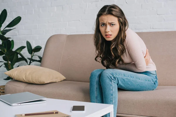 Jonge Vrouw Camera Kijken Terwijl Het Lijden Aan Buikpijn Thuis — Stockfoto