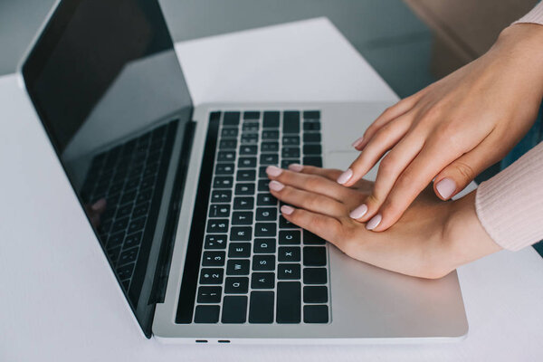 close-up partial view of woman rubbing hand while using laptop with blank screen