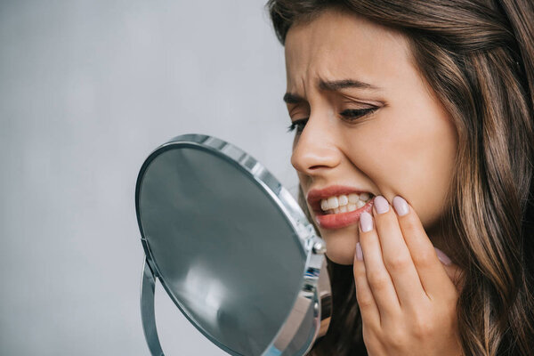 close-up view of young woman having toothache and looking at mirror