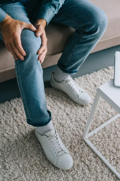 Schnappschuss Von Mann Der Auf Sofa Sitzt Und Unter Knieschmerzen — Stockfoto