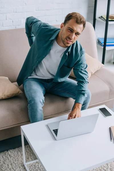 Man Suffering Back Pain Looking Camera While Using Laptop Home — Stock Photo, Image