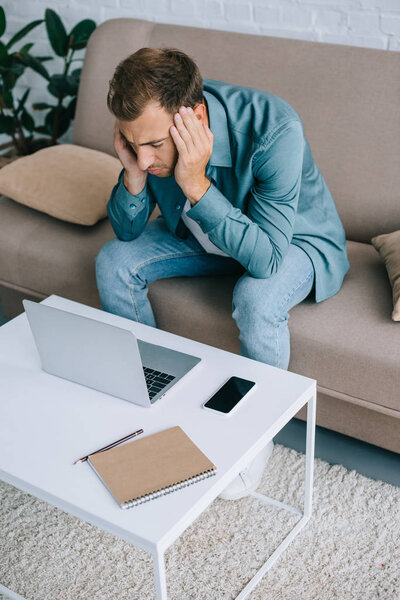 высокий угол зрения молодого человека с головной болью с помощью ноутбука дома
