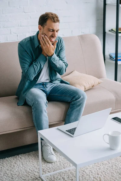 Young Man Suffering Tooth Pain While Using Laptop Home — Stock Photo, Image