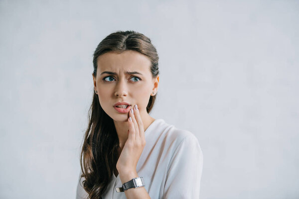attractive young woman suffering from toothache and looking away
