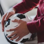 Tiro cortado de homem de negócios segurando bola de futebol no escritório