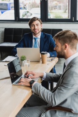 dizüstü bilgisayarlar kullanarak ve birlikte çalışma office elbiseli Genç iş adamları 