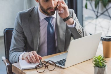 smartphone ile konuşmak ve dizüstü bilgisayar kullanma office işadamı kırpılmış atış