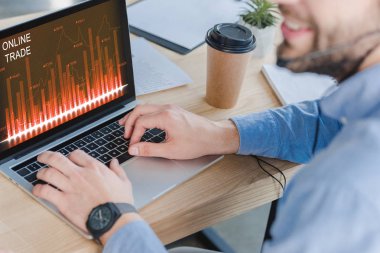 Kırpılan atış ile online ticaret Web sitesinde ekran dizüstü kullanarak kulaklık gülümseyen iş adamı 