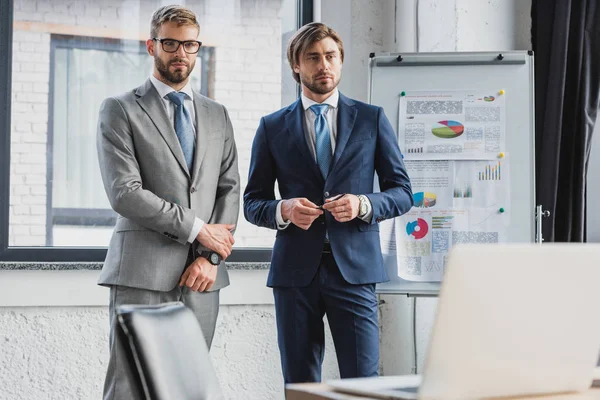 Τρεις Όμορφος Νέους Επιχειρηματίες Στα Κοστούμια Στέκεται Μαζί Στο Γραφείο — Φωτογραφία Αρχείου