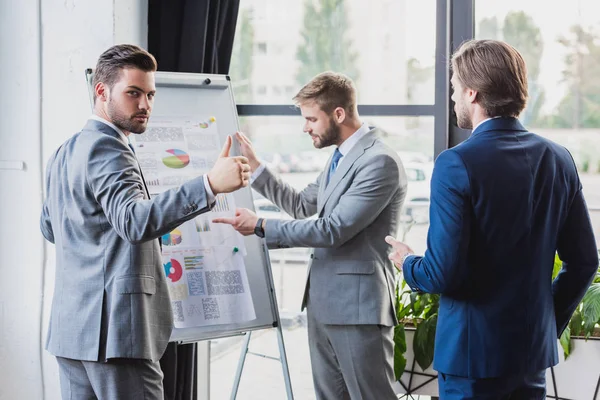 Young Businessman Showing Thumb Looking Camera While Working Colleagues Whiteboard — Stock Photo, Image