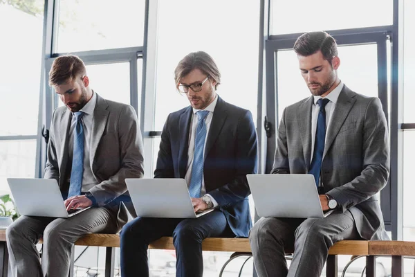 Tres Jóvenes Hombres Negocios Trajes Sentados Usando Computadoras Portátiles — Foto de Stock