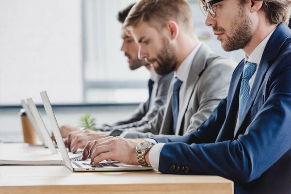 cropped shot of focused young businessmen working with laptops in office