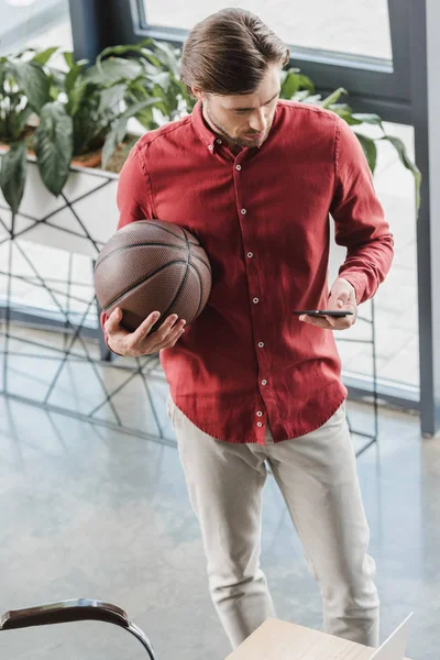 Vysoký Úhel Pohledu Podnikatel Držení Basketbalového Míče Pomocí Smartphone Kanceláři — Stock fotografie