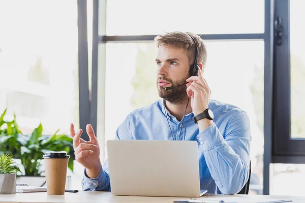 Bonito Jovem Operador Call Center Fone Ouvido Usando Laptop Olhando — Fotografia de Stock