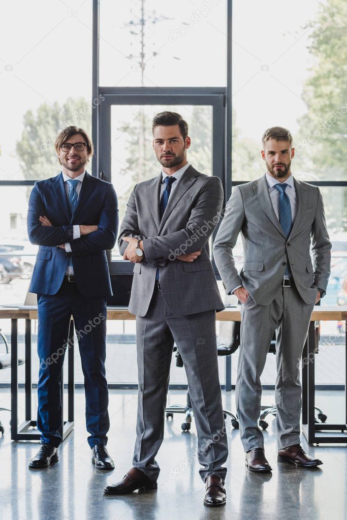 confident young businessmen in formal wear standing together and looking at camera in office