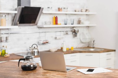 Mutfak tezgahının üzerinde laptop, smartphone ve kahve pot