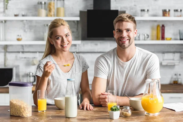 Χαμογελαστά Ζευγάρι Έχοντας Πρωινό Στην Κουζίνα Και Βλέπουν Φωτογραφικών Μηχανών — Φωτογραφία Αρχείου