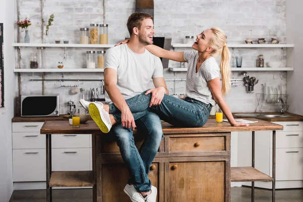 laughing couple hugging and sitting on kitchen counter