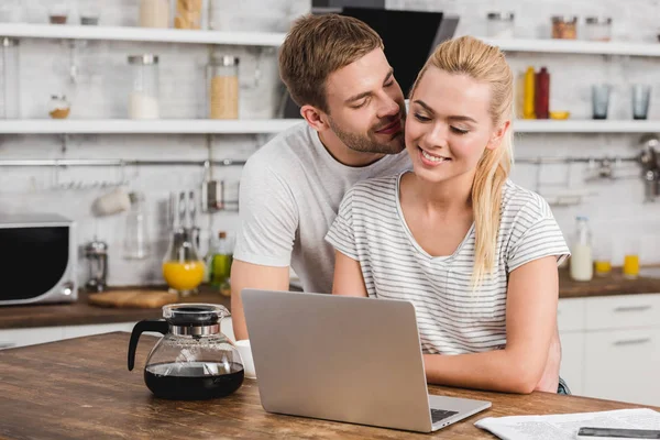 Novio Abrazo Sonriente Novia Cocina Mientras Ella Trabaja Con Ordenador — Foto de Stock