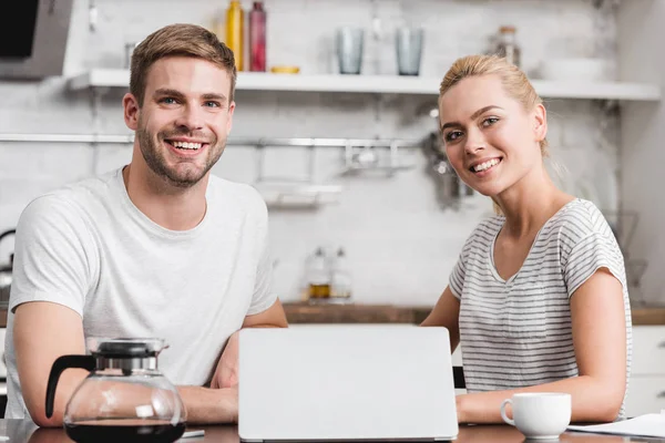 快乐的年轻夫妇使用笔记本电脑和微笑在一起的相机 — 免费的图库照片