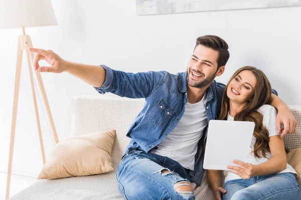 Joven Feliz Señalando Con Dedo Novia Con Tableta Digital Sofá — Foto de stock gratis