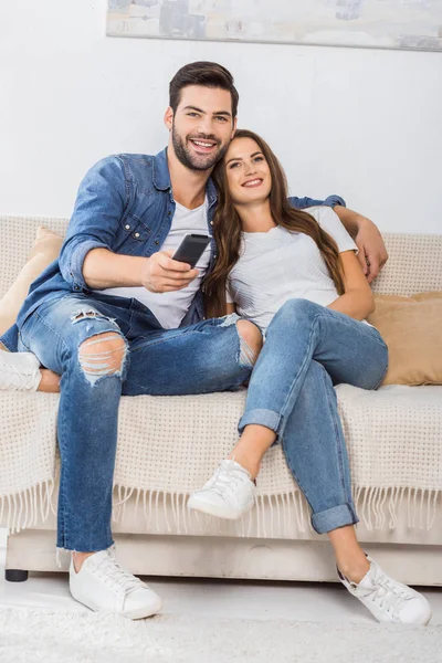 Sorridente Giovane Coppia Con Telecomando Guardando Sul Divano Casa — Foto Stock