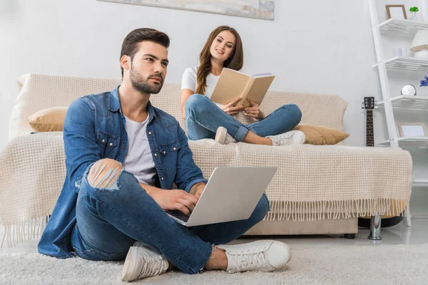 Zelfverzekerde Jonge Man Met Laptop Zittend Vloer Terwijl Zijn Vriendin — Gratis stockfoto