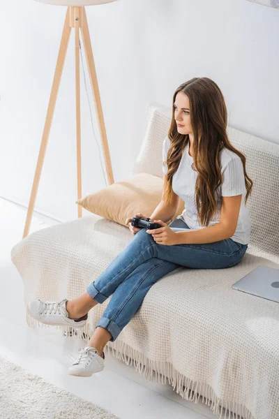 魅力的な若い女性は 自宅でソファにジョイスティックでビデオ ゲームをプレイのハイアングル  — 無料ストックフォト
