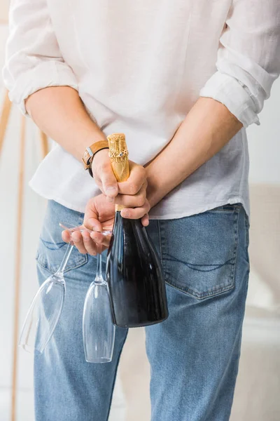 Imagen Recortada Hombre Escondiendo Botella Champán Copas Sus Espaldas Casa — Foto de Stock