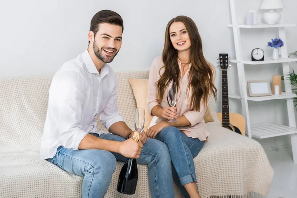 Feliz Jovem Casal Comemorando Com Garrafa Champanhe Óculos Sofá Casa — Fotografia de Stock